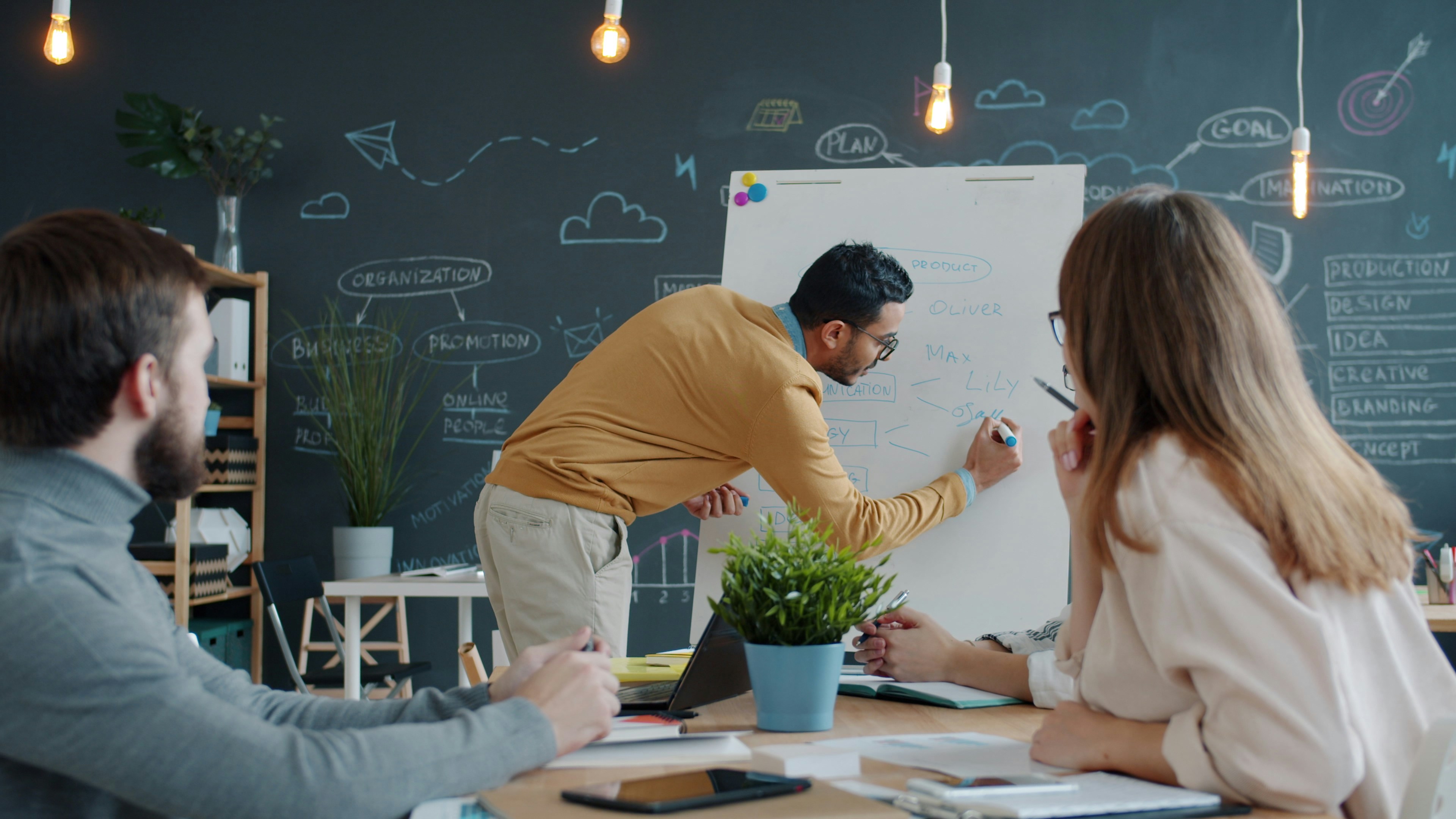 Consultant presenting near a whiteboard with sticky notes during a process mapping workshop